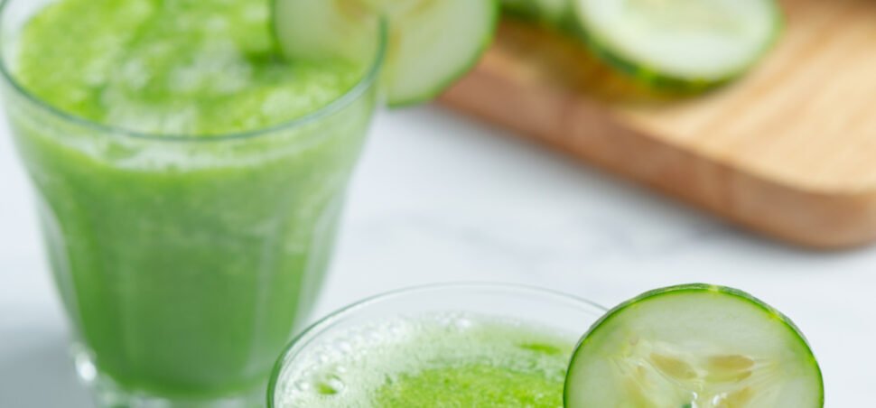 Glass of fresh cucumber juice on marble background